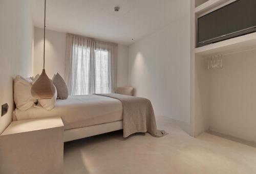 a white bedroom with a bed and a window at Hotel Avenida in Zaragoza