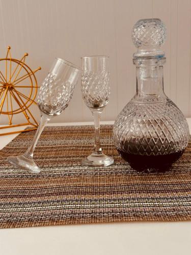 three wine glasses and a bottle on a table at Luxury Residence Likani in Borjomi