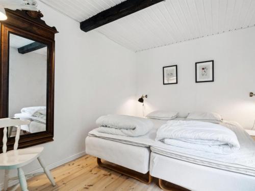 a white bedroom with a mirror and a bed at Holiday Home Héléne - 2-4km from the sea by Interhome in Åkirkeby