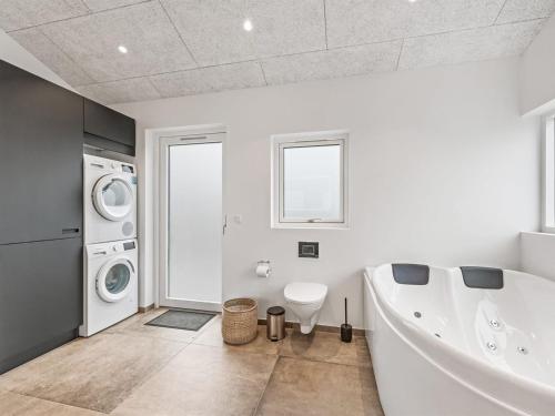 a white bathroom with a tub and a washing machine at Holiday Home Chenoa - 350m from the sea by Interhome in Ringkøbing