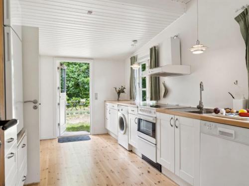 a kitchen with white cabinets and a wooden floor at Holiday Home Heidl - 1-3km to the inlet by Interhome in Rørvig