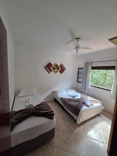 two beds in a room with a window at Pousada Aconchego Bertioga in Bertioga
