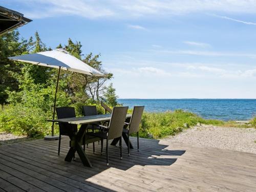 a table and chairs with an umbrella on a wooden deck at Holiday Home Antonina - 10m from the sea by Interhome in Martofte