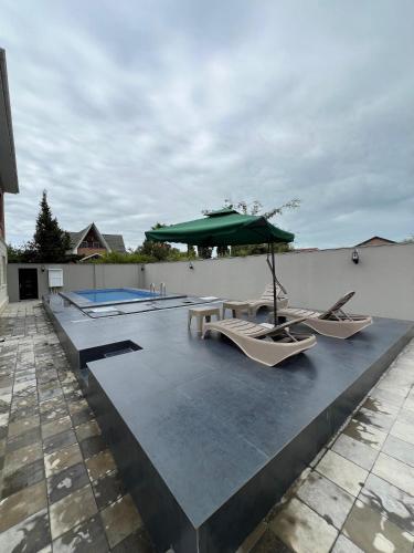 a patio with a table and an umbrella and chairs at Red Brick House in Şürük