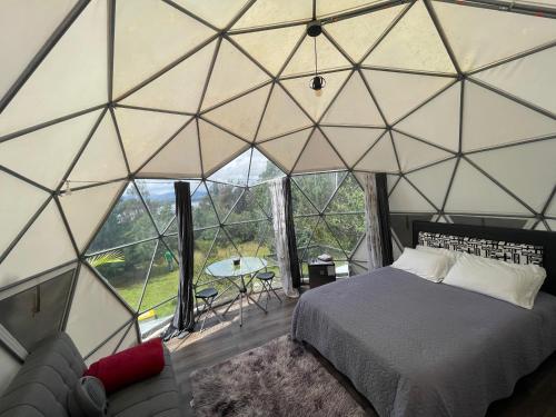 a bedroom in a dome tent with a bed and a couch at El Alpino Cabaña Glamping & Camping in Guatavita