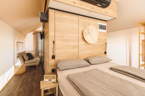 a bedroom with a large bed and a chair at Glamping Resort Olive and Sea in Bibinje