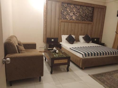 a bedroom with a bed and a couch and a table at Hotel Rise Inn in Karachi