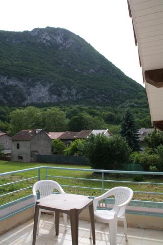 a table and two chairs on a balcony with a mountain at La petite auberge de niaux in Niaux