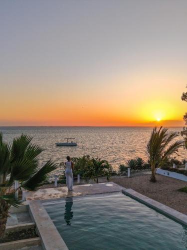 ミチャンビにあるVilla Claudiusの夕日を眺めながらプールの横に立つ女性