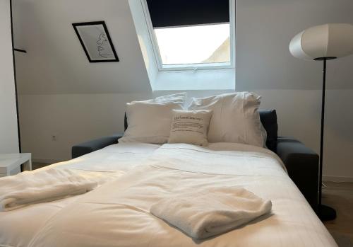 a bed with white sheets and pillows and a window at Top-Floor Hideaway for Two in Karlsruhe-Mühlburg - APOLONIAliving - Apt3 in Karlsruhe