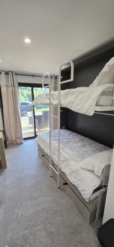 two bunk beds in a room with a window at L'Aiguillon - Studio avec Jacuzzi pour 2 personnes et enfants proche stations - Idéal couple avec 1 enfant in Saint-Jean-de-Sixt