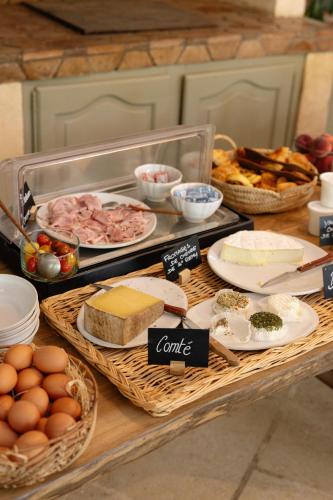 Una mesa con queso, pan, huevos y otros alimentos. en Hotel Moulin d'Aure, en Saint-Rémy-de-Provence
