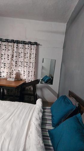 a bedroom with a bed and a table and a mirror at Swanky Sojourns Homestay in Kolhapur