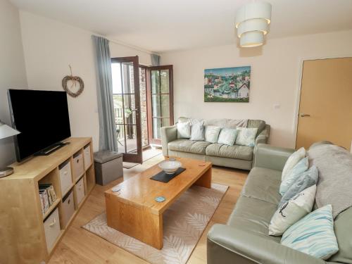 a living room with a couch and a tv at Awel y Môr in Burry Port
