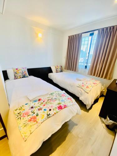 a bedroom with two beds with floral sheets at Omori Happy Smile Hotel in Wada