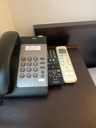 a telephone and two remote controls sitting on a table at Omori Happy Smile Hotel in Wada