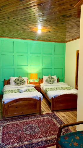 a bedroom with two beds and a green wall at Umda Hotel Montana in Nathia Gali