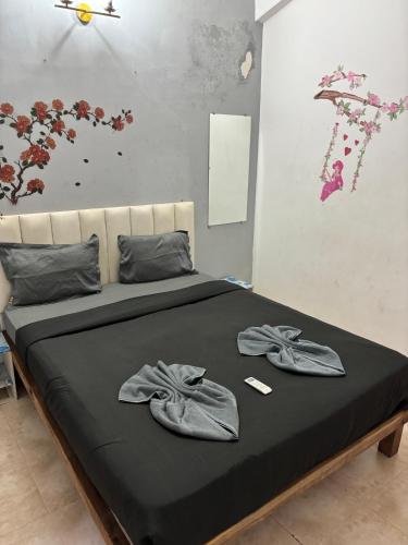a bed with a black blanket and two slippers on it at M R Holidays Apartments in Arpora