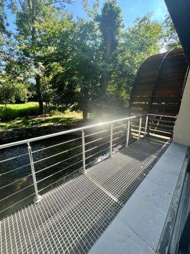 a train platform with a metal railing and trees at Chambres de hôte les moulin la paille in Veyre-Monton