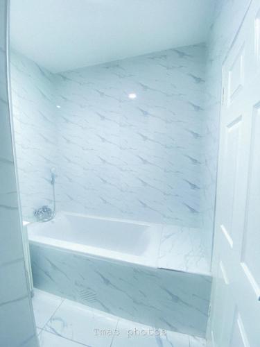 a white tub in a bathroom with a white wall at Cozy Up on 5th in Harare