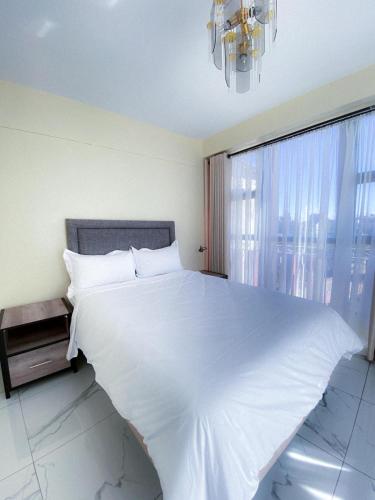 a large white bed in a bedroom with a window at Cozy Up on 5th in Harare