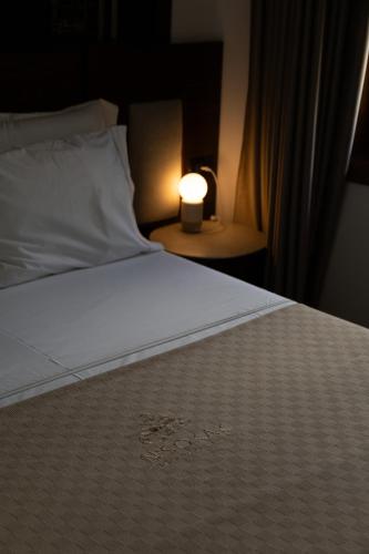 a bed with a white sheet and a candle on a table at N'SOKAK Boutique Hotel in Gjirokastër