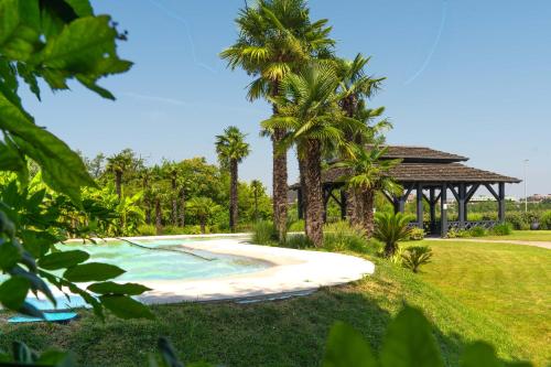 a resort pool with palm trees and a gazebo at Royal Garden Assago Milano in Assago
