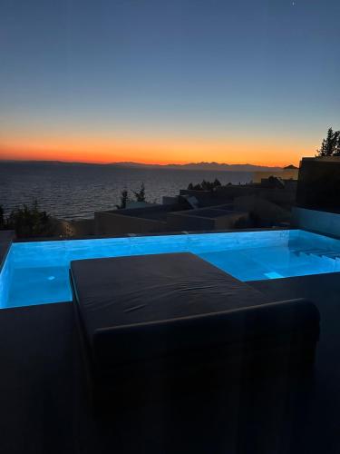 a blue swimming pool with the sunset in the background at Zante Fiore Suites in Xirokástellon