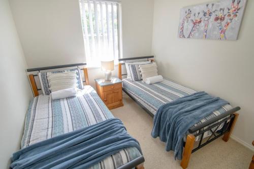 a bedroom with two beds and a lamp in it at Coastal Garden Villa in Albany