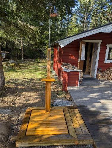 a wooden stand in front of a red house at Log Cabin with hot-tub & Sauna, secluded location in Ryd
