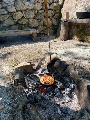 a grill with a pizza cooking on top of it at Log Cabin with hot-tub & Sauna, secluded location in Ryd
