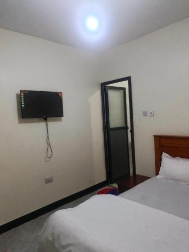 a bedroom with two beds and a television on the wall at Old Moshi Park in Arusha