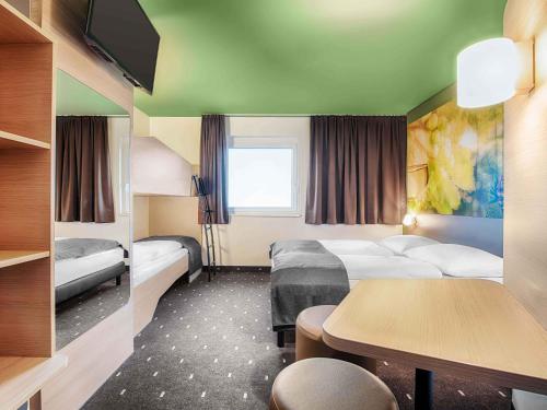 a hotel room with two beds and a table at B&B HOTEL Baden-Airpark in Rheinmunster