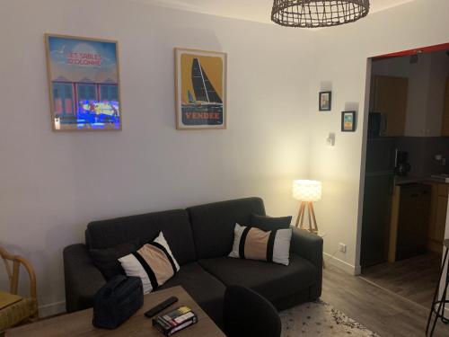 a living room with a couch and a tv at Les Sables d'Olonne, Les Présidents, charmant appartement lumineux, plage 150 m. in La Rudelière