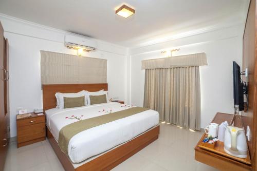a bedroom with a large bed and a television at The Fog Munnar (Resort & Spa) in Munnar