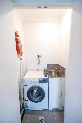 a laundry room with a sink and a washing machine at Green Olive in Ettalong Beach
