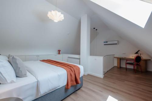 a white bedroom with a bed and a table at Artifact Apart Hotel in Tbilisi City