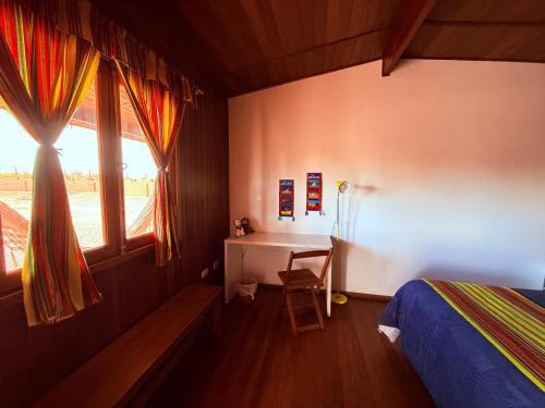 a bedroom with a bed and a desk and a window at MAKTVB - EcoLodge San Pedro de Atacama in San Pedro de Atacama