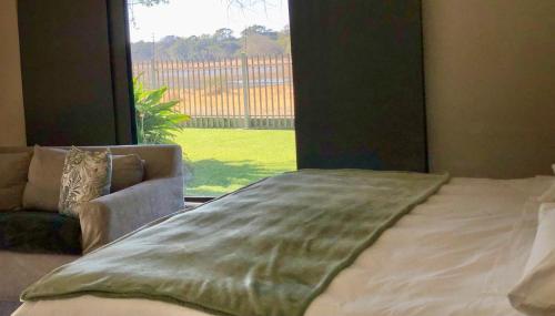 a bed in a room with a large window at Riverise Guesthouse in Maun