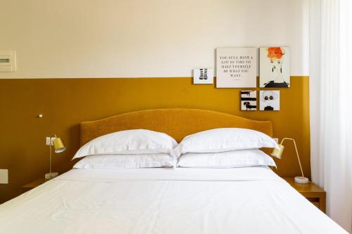 a bedroom with a bed with white sheets and pillows at Lu. b&b in Cervia