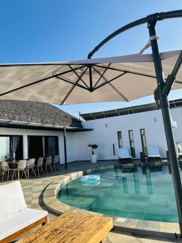 a pool with an umbrella and chairs and a table at Villa ANAYA in Nosy Be