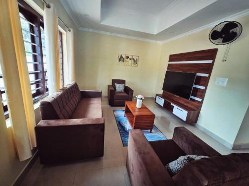 a living room with couches and a flat screen tv at Tranquil Nest Villa - Wayanad in Kalpetta