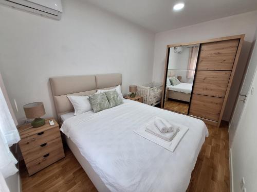 a bedroom with a large white bed and a mirror at Apartman IGOR Trebinje in Trebinje
