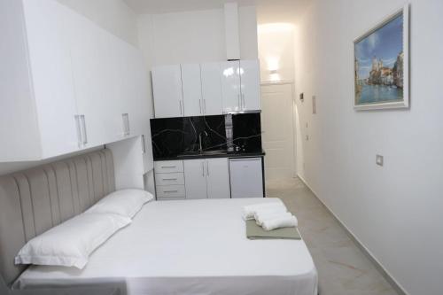 a white bedroom with a white bed and a kitchen at Xhani's Rooms Durres in Durrës