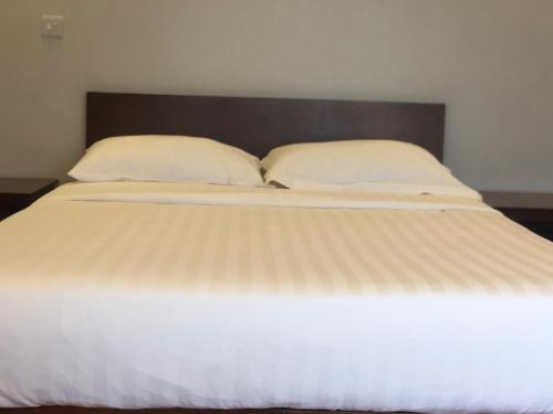 a large white bed with two pillows on it at Enkombe Place in Kampala