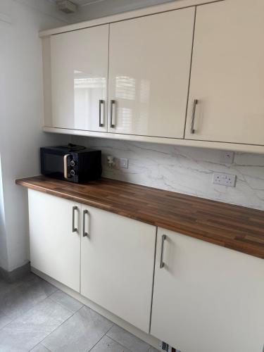 a kitchen with white cabinets and a microwave on a counter at Beautiful Apartment in Burstwick