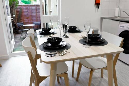 a wooden table with chairs and plates and wine glasses at 4 Guests - Pet Friendly Retreat in Thornton Heath in Thornton Heath