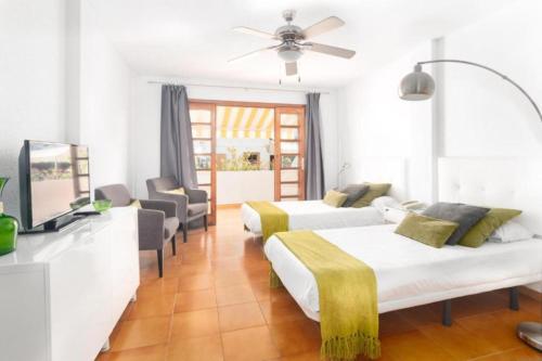 a white room with two beds and a television at Moderno estudio con Terraza y Piscina en Costa Adeje in Costa de Adeje