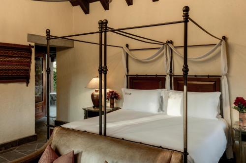 a bedroom with a large canopy bed with white pillows at Las Casitas, A Belmond Hotel, Colca Canyon in Yanque