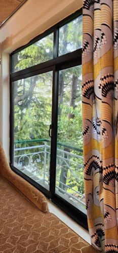 a window with a curtain in a room at Mezbaan guest house in Nathia Gali
